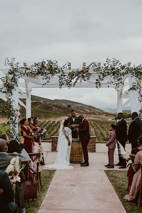  Letitia and Zach’s romantic vineyard burgundy + rose wedding – bride in her lace gown with long sleeves and the groom in a burgundy shawl lapel tuxedo 