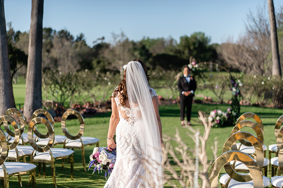  one bride in a black women’s tuxedo with a black diamond shaped bow tie and one bride in a white mermaid style gown with a beaded bodice and strapless neckline 