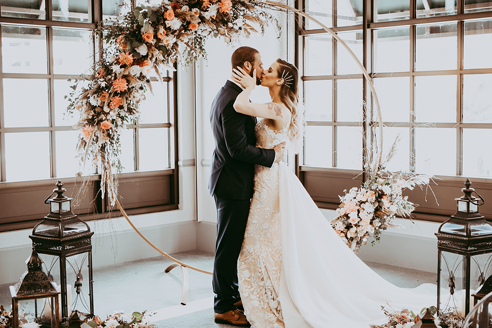  groom in a navy suit and bow tie and the bride in a white lace strapless gown at ceremony