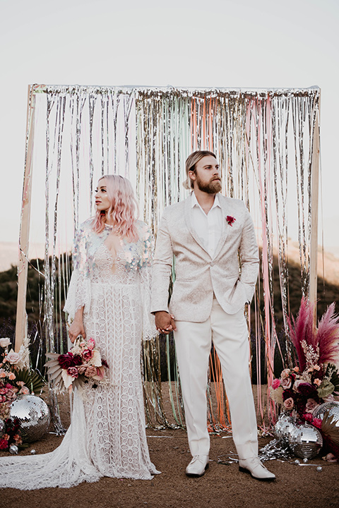  the bride in a fun sequin gown with a faux fur coat and the groom in an ivory paisley tuxedo
