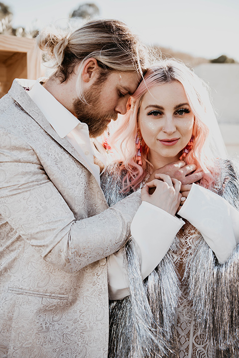  the bride in a fun sequin gown with a faux fur coat and the groom in an ivory paisley tuxedo