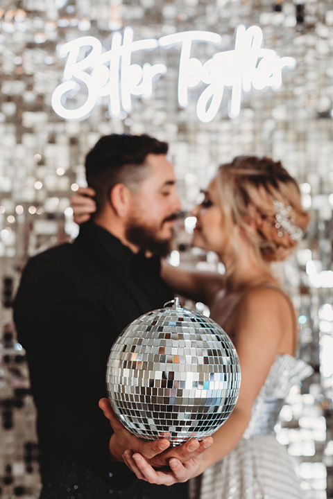  bride in a silver gown with her hair in a braided bun and the groom in an all-black suit