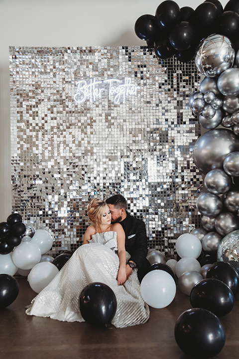  bride in a silver gown with her hair in a braided bun and the groom in an all-black suit 