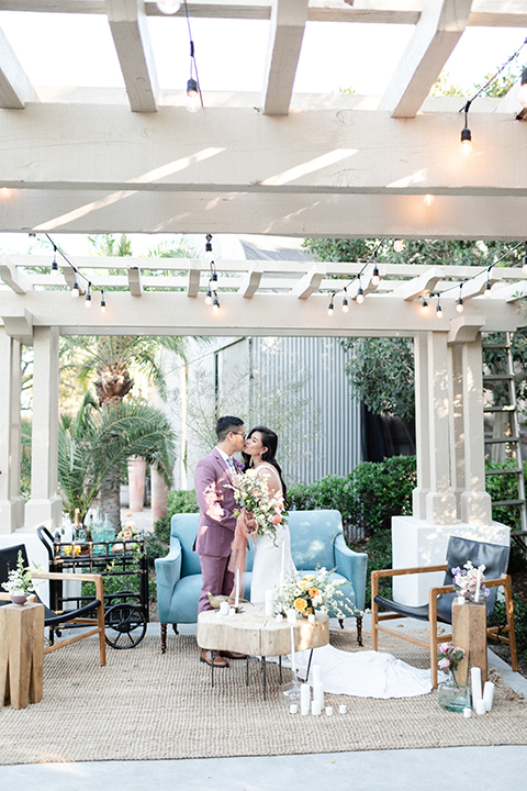  bride in a formfitting gown with a high neck and a long train groom in a rose pink suit and a light blue floral tie 