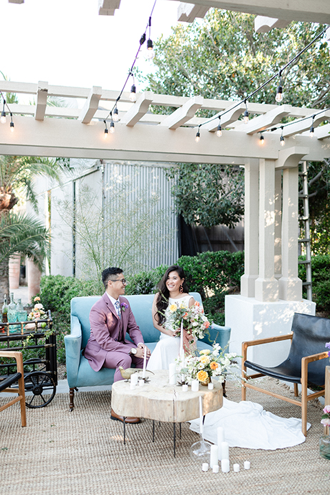  bride in a formfitting gown with a high neck and a long train groom in a rose pink suit and a light blue floral tie 