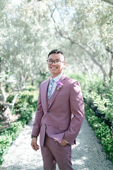  bride in a formfitting gown with a high neck and a long train groom in a rose pink suit and a light blue floral tie 