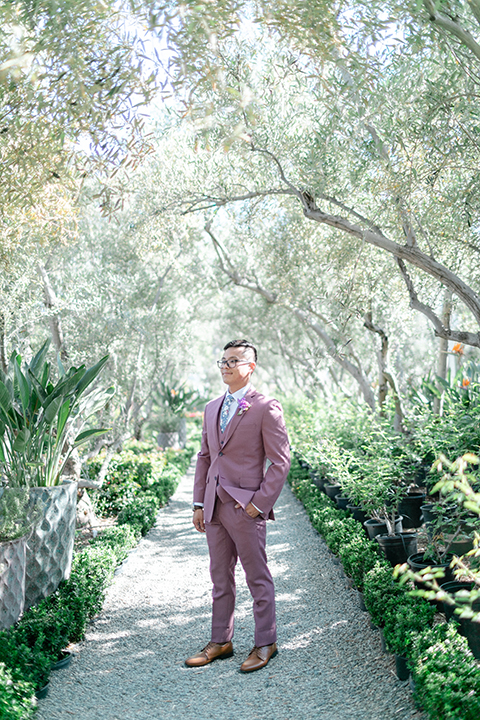  bride in a formfitting gown with a high neck and a long train groom in a rose pink suit and a light blue floral tie 