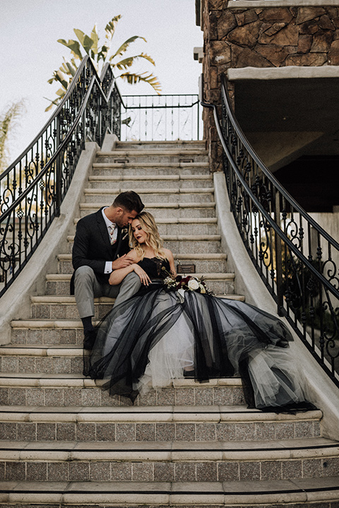  bride in a black and grey gown with a black tulle veil and the groom in a asphalt grey coat with light grey pants and floral white tie