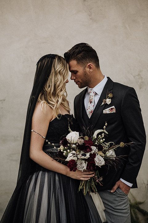  bride in a black and grey gown with a black tulle veil and the groom in a asphalt grey coat with light grey pants and floral white tie