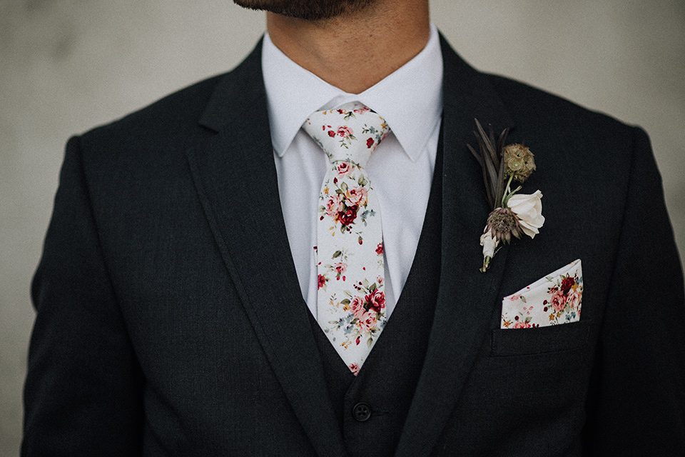  bride in a black and grey gown with a black tulle veil and the groom in a asphalt grey coat with light grey pants and floral white tie 