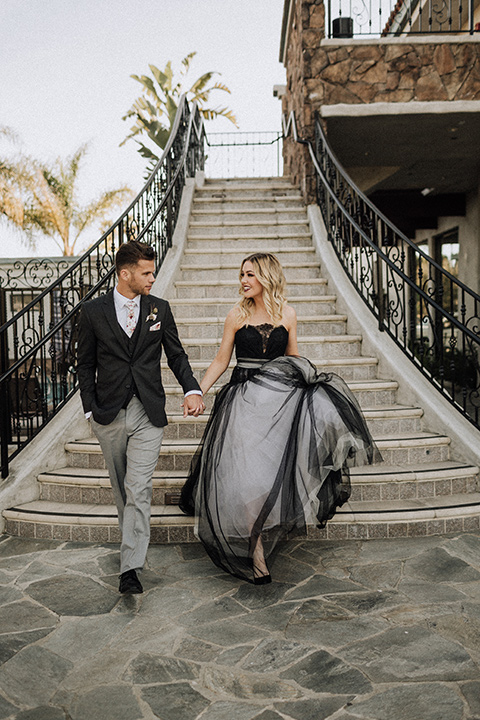  bride in a black and grey gown with a black tulle veil and the groom in a asphalt grey coat with light grey pants and floral white tie 