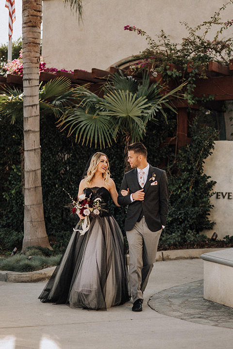  bride in a black and grey gown with a black tulle veil and the groom in a asphalt grey coat with light grey pants and floral white tie 