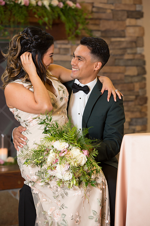  bride in a modern formfitting gown with cap sleeves and a high neck and the groom in a green suit with a floral tie