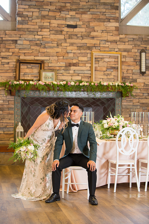  bride in a modern formfitting gown with cap sleeves and a high neck and the groom in a green suit and floral tie 