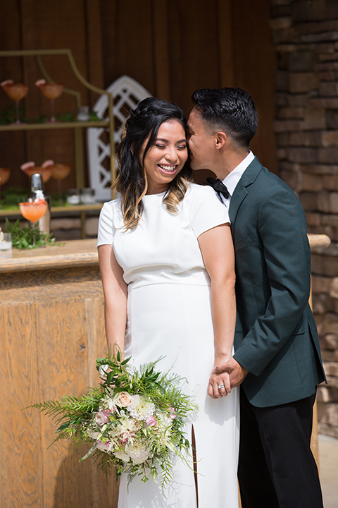  bride in a modern formfitting gown with cap sleeves and a high neck and the groom in a green suit and floral tie 