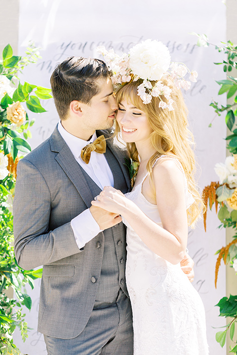  groom in a café brown suit and a gold velvet bow tie bride in a white silk gown with a cape overlay