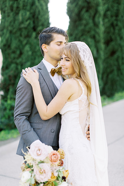  groom in a café brown suit and a gold velvet bow tie bride in a white silk gown with a cape overlay 