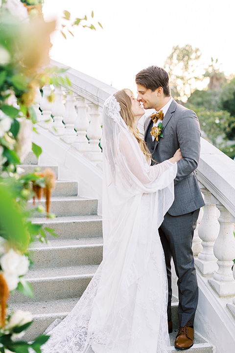  groom in a café brown suit and a gold velvet bow tie bride in a white silk gown with a cape overlay 