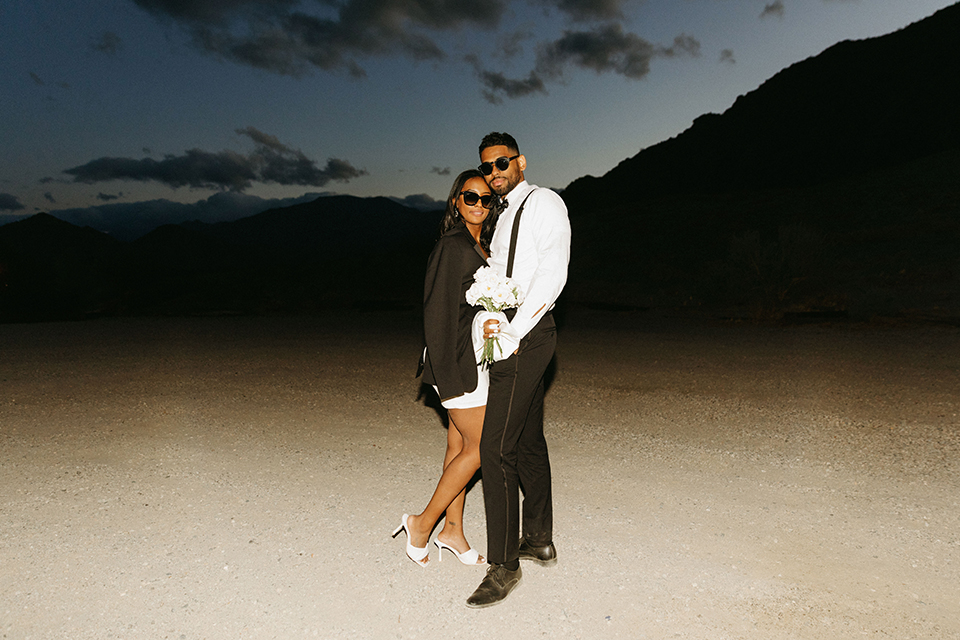  palm spring elopement with a chic black tie vibe the groom in a black tuxedo and the bride in a short tuxedo coat dress 