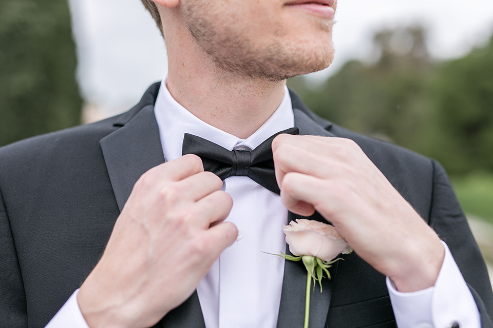  groom in a black tuxedo and a black bow tie and the bride in an a-line gown with sleeves 