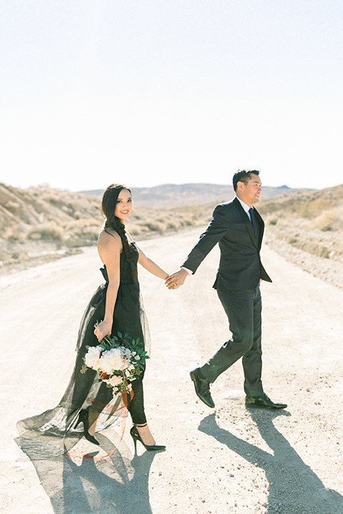  bride in a black jumpsuit with a tulle overlay and the groom in a navy shawl lapel tuxedo with a black long tie