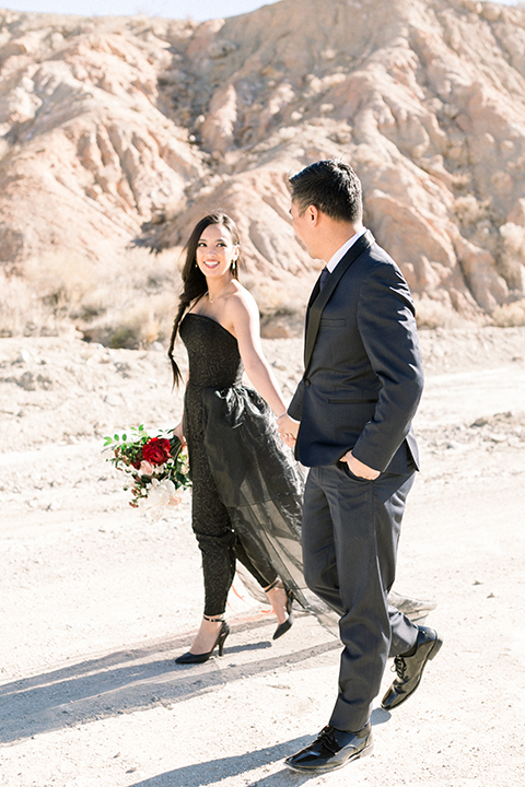  bride in a black jumpsuit with a tulle overlay and the groom in a navy shawl lapel tuxedo with a black long tie