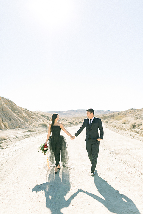  bride in a black jumpsuit with a tulle overlay and the groom in a navy shawl lapel tuxedo with a black long tie 