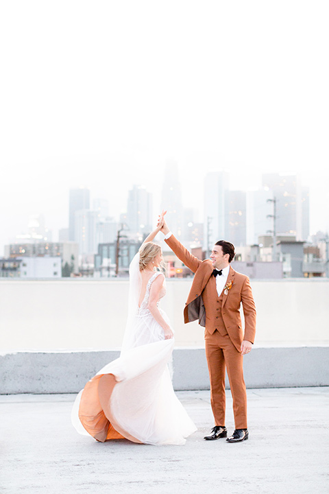  the bride in a white gown with an illusion neckline and hair in a low bun, the groom in a caramel brown suit with a chocolate brown bow tie 