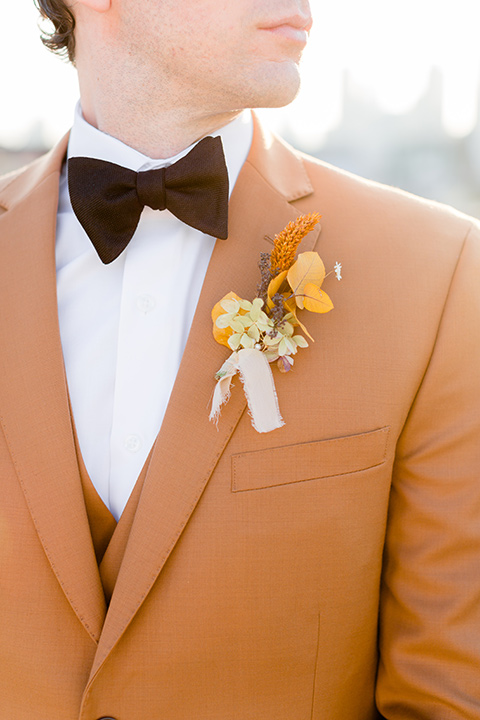  the bride in a white gown with an illusion neckline and hair in a low bun, the groom in a caramel brown suit with a chocolate brown bow tie 