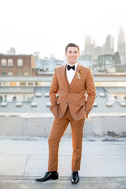  the bride in a white gown with an illusion neckline and hair in a low bun, the groom in a caramel brown suit with a chocolate brown bow tie