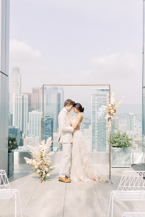  skyline dream with the bride in a formfitting lace gown and the groom in a tan suit 