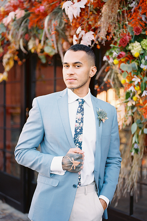  a groom in a blue notch lapel coat and charcoal grey pants and the other groom in a light blue coat and tan pants 