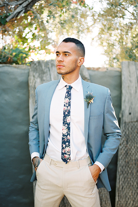  a groom in a blue notch lapel coat and charcoal grey pants and the other groom in a light blue coat and tan pants