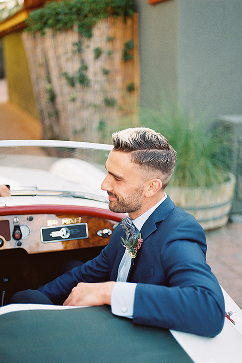  a groom in a blue notch lapel coat and charcoal grey pants and the other groom in a light blue coat and tan pants 