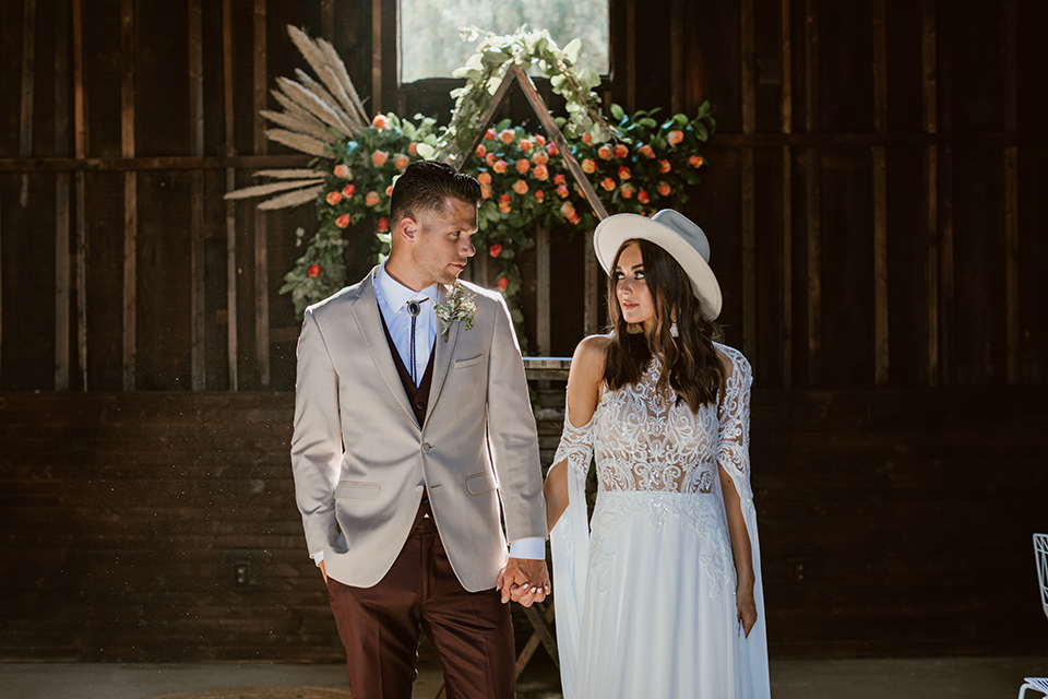  bride in a bohemian gown with chunky earrings and the groom in a ivory paisley tuxedo with burgundy pants and vest 