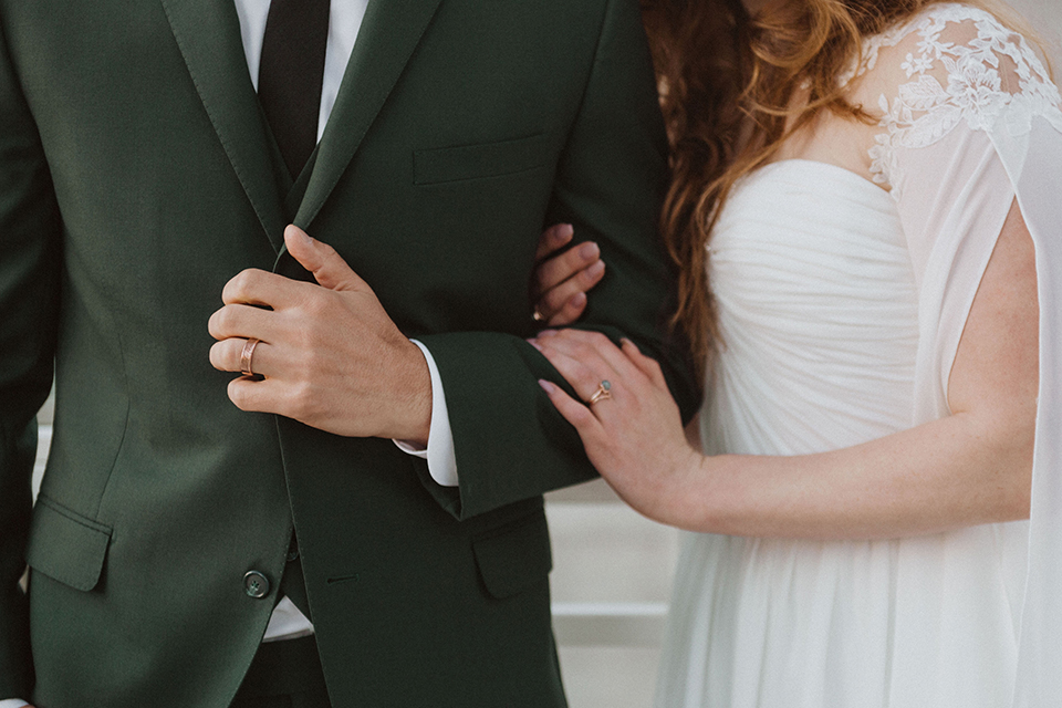  bride in a white ballgown and the groom in a green suit with a chocolate long tie 