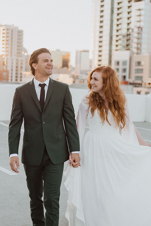  bride in a white ballgown and the groom in a green suit with a chocolate long tie 