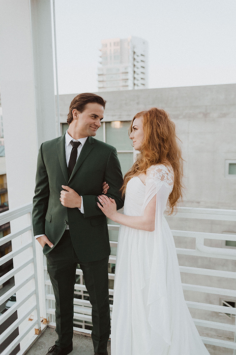  bride in a white ballgown and the groom in a green suit with a chocolate long tie 