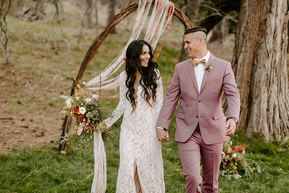  bride in a lace gown with long sleeves and the groom in a rose pink suit with a gold velvet bow tie 
