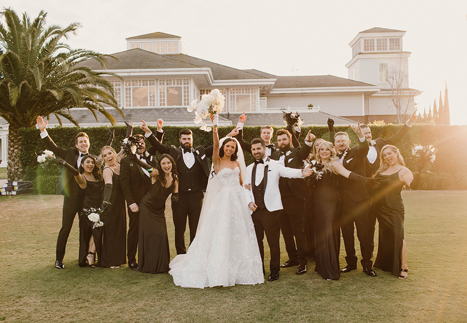  a chic black and white wedding with modern touches with the groom in a white tuxedo and the bride in a white ballgown and the bridesmaids and groomsmen in black dresses/tuxedos – bridal party 