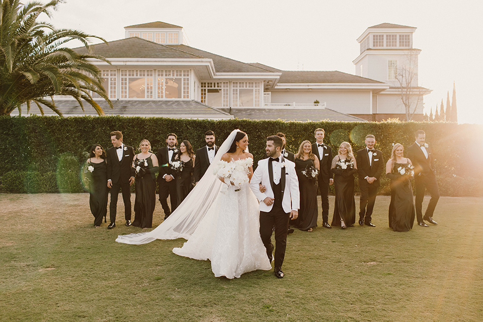  a chic black and white wedding with modern touches with the groom in a white tuxedo and the bride in a white ballgown and the bridesmaids and groomsmen in black dresses/tuxedos – bridal party 