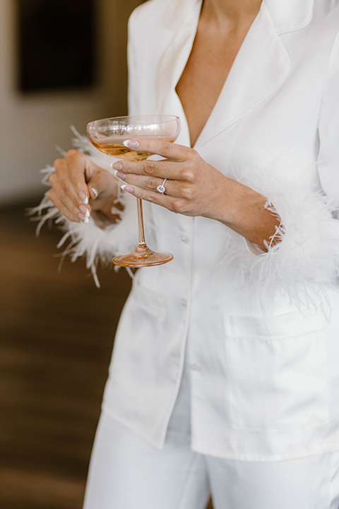  a chic black and white wedding with modern touches with the groom in a white tuxedo and the bride in a white ballgown and the bridesmaids and groomsmen in black dresses/tuxedos – bride in her getting ready robe 