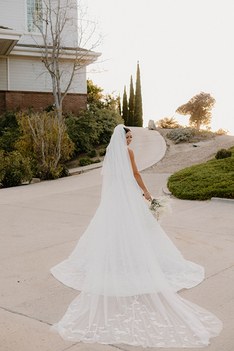  a chic black and white wedding with modern touches with the groom in a white tuxedo and the bride in a white ballgown and the bridesmaids and groomsmen in black dresses/tuxedos – bride in her gown and veil 