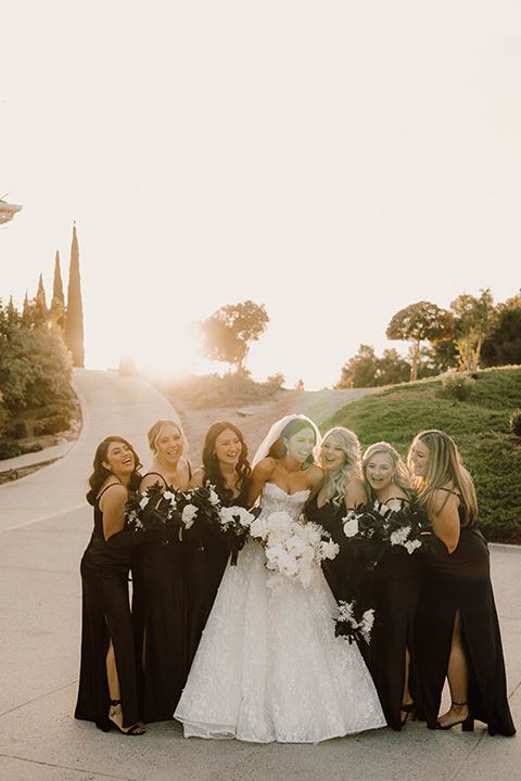  a chic black and white wedding with modern touches with the groom in a white tuxedo and the bride in a white ballgown and the bridesmaids and groomsmen in black dresses/tuxedos – bride and the bridesmaids 