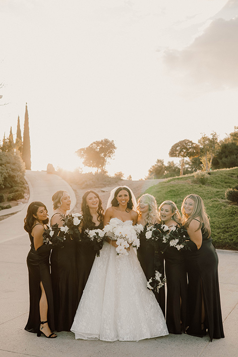  a chic black and white wedding with modern touches with the groom in a white tuxedo and the bride in a white ballgown and the bridesmaids and groomsmen in black dresses/tuxedos – bride and bridesmaids 