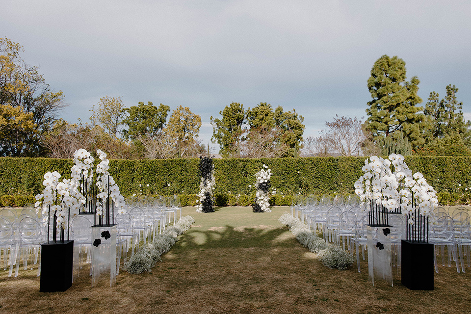  a chic black and white wedding with modern touches with the groom in a white tuxedo and the bride in a white ballgown and the bridesmaids and groomsmen in black dresses/tuxedos – ceremony space 