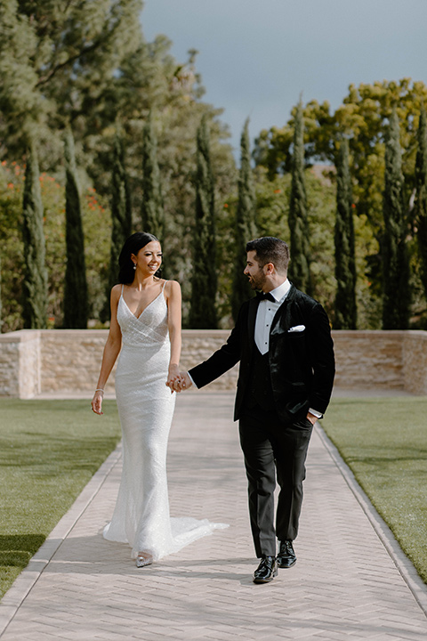  a chic black and white wedding with modern touches with the groom in a white tuxedo and the bride in a white ballgown and the bridesmaids and groomsmen in black dresses/tuxedos – bride and groom in their party outfits – the groom in a black velvet tuxedo and the bride in a sparkling fitted gown 