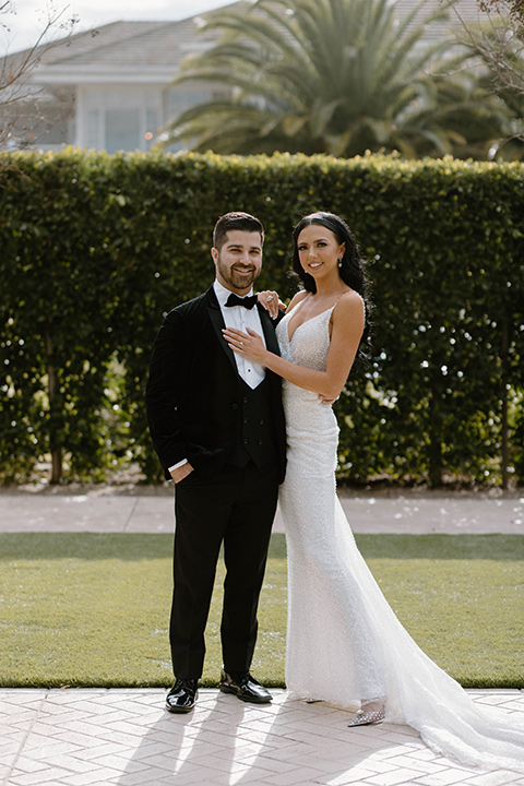  a chic black and white wedding with modern touches with the groom in a white tuxedo and the bride in a white ballgown and the bridesmaids and groomsmen in black dresses/tuxedos – bride and groom in their party outfits – the groom in a black velvet tuxedo and the bride in a sparkling fitted gown 
