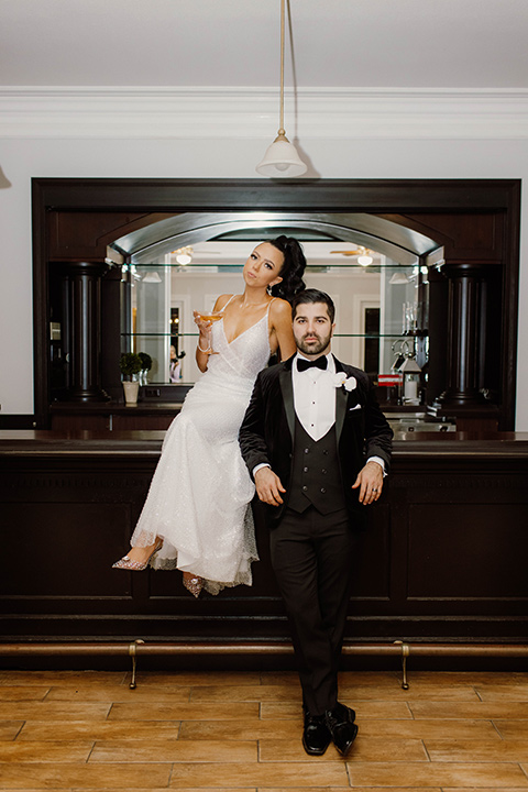  a chic black and white wedding with modern touches with the groom in a white tuxedo and the bride in a white ballgown and the bridesmaids and groomsmen in black dresses/tuxedos – bride and groom in their party outfits – the groom in a black velvet tuxedo and the bride in a sparkling fitted gown 
