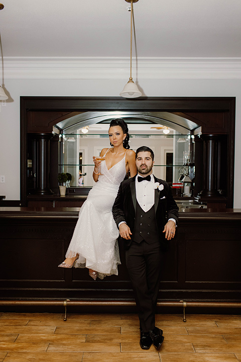  a chic black and white wedding with modern touches with the groom in a white tuxedo and the bride in a white ballgown and the bridesmaids and groomsmen in black dresses/tuxedos – bride and groom in their party outfits – the groom in a black velvet tuxedo and the bride in a sparkling fitted gown 